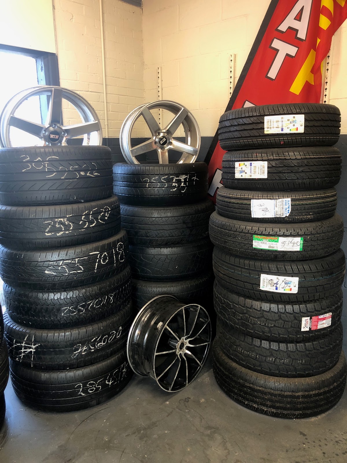 Piedmont Tires — showroom-floor tire and wheel inventory with chrome rims and a red banner backdrop