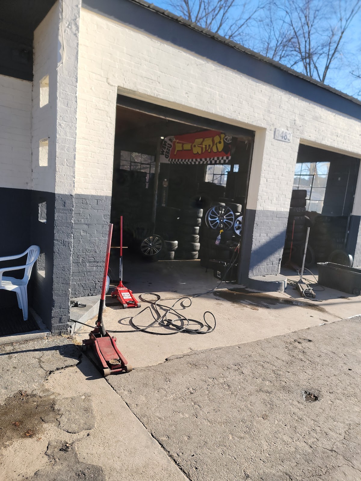 Piedmont Tires — open service bay with a red Pittsburgh floor jack, air hoses, and the Piedmont Tires banner over the doorway